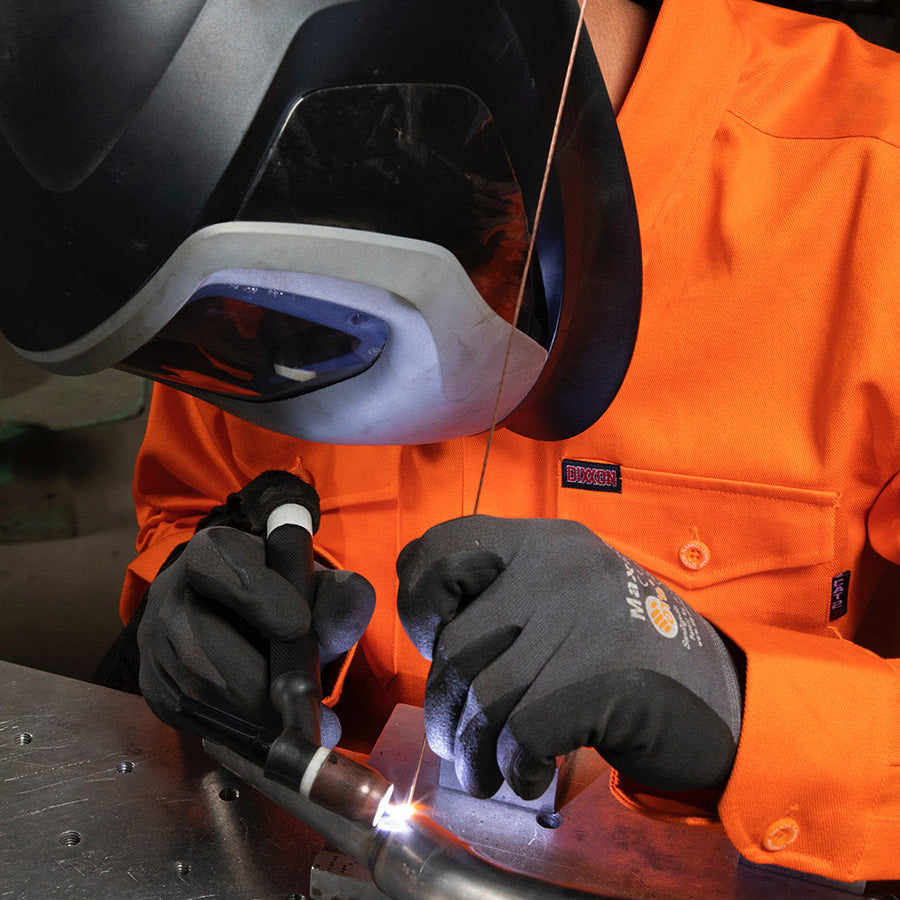 Dixxon Canada. Workforce FR Flannel Safety Orange - Mens. Model wearing the safety orange FR flannel while welding, showcasing its flame-resistant properties and durable design for hazardous work environments.
